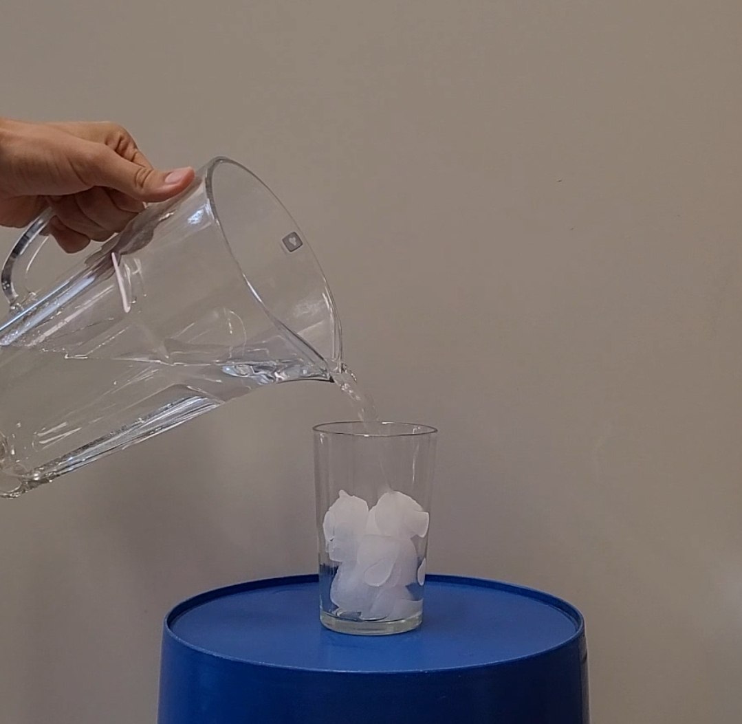 glass with ice and water pouring over
